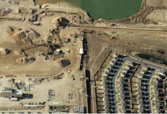 Aerial view of a sand and gravel operation directly adjacent to a dense new housing subdivision.